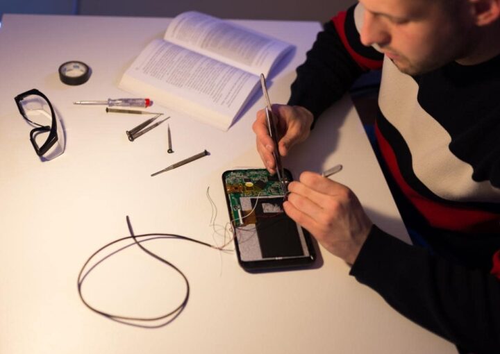 a man sitting at a table working on a cell phone
