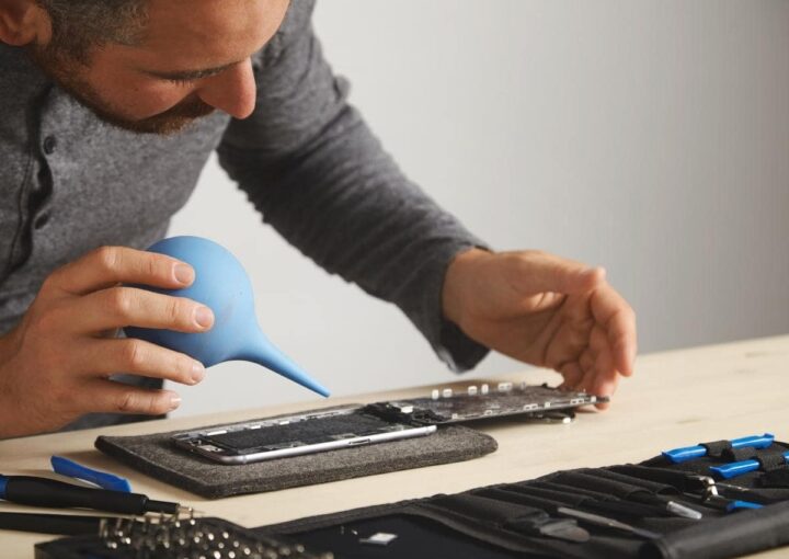 A man sitting at a table working on a cell phone