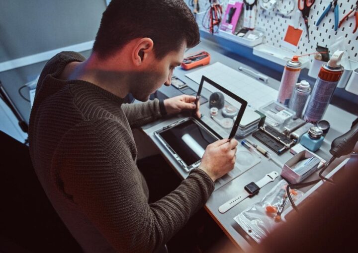 a man sitting at a table working on a tablet