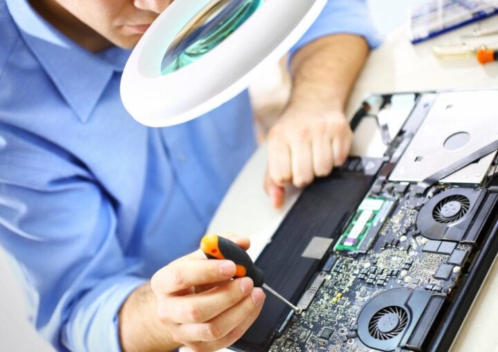 A man working on a laptop with a magnifying glass