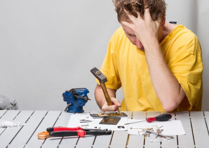 A mechanic sitting at a workbench with various tools spread out in front of him