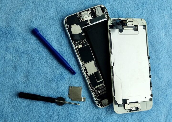 A cracked smartphone rests on a vibrant blue background