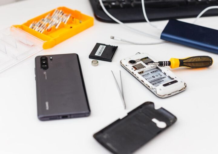 A sleek black keyboard and various electronic gadgets neatly arranged on a white desk