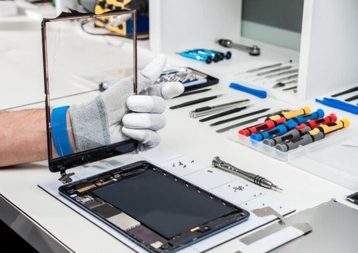 A man is working on a laptop with tools