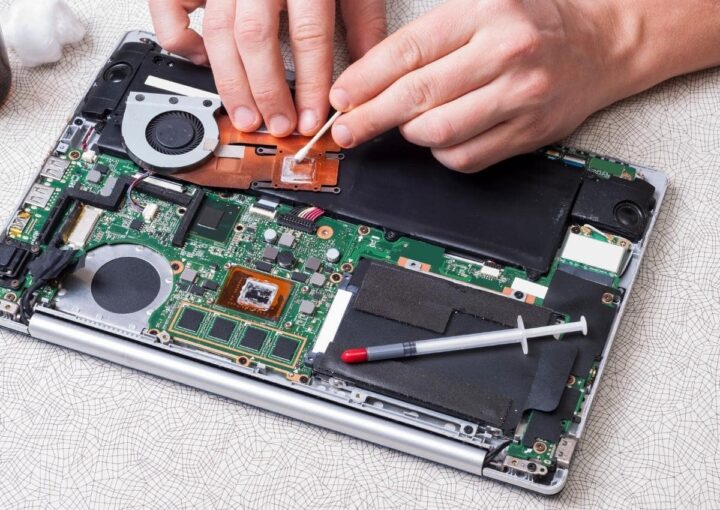 A person working on a laptop with a screwdriver, fixing the hardware